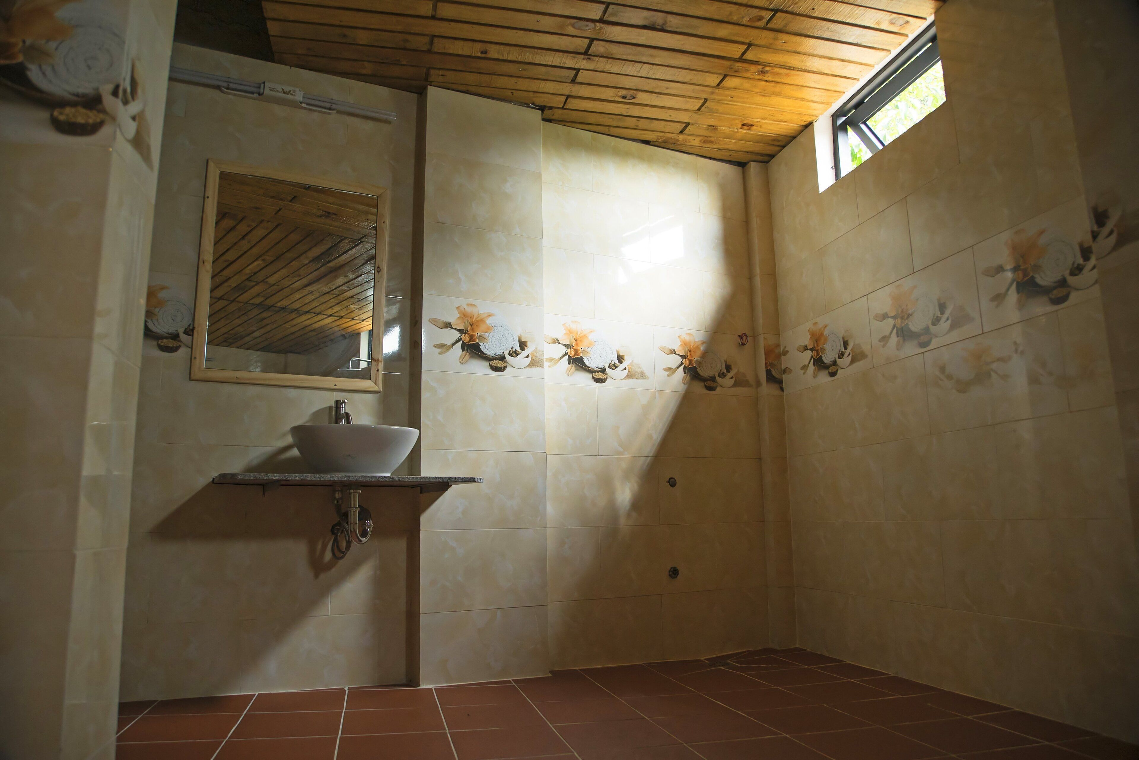 A bathroom with a wooden ceiling, a sink with a mirror, and decorative tiles.