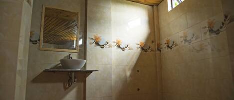 A bathroom with a wooden ceiling, a sink with a mirror, and decorative tiles.