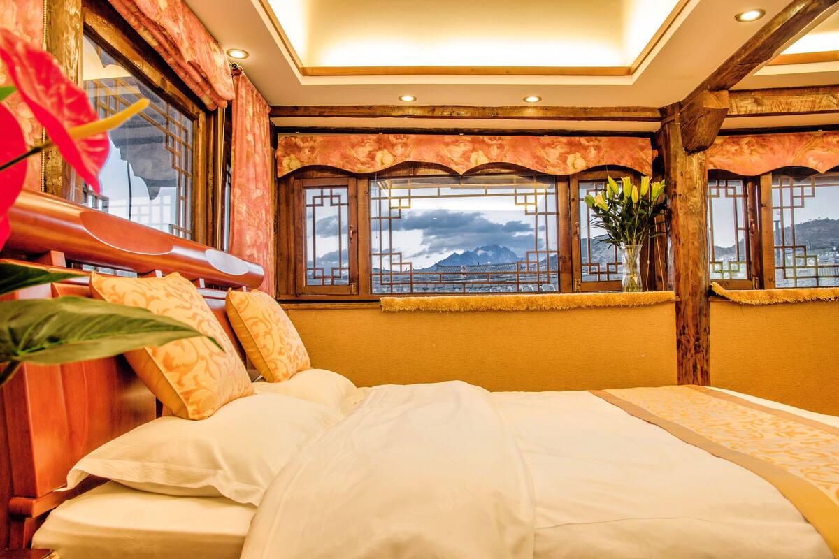 Une chambre d’hôtel avec un lit, de grandes fenêtres et une vue sur les montagnes.
