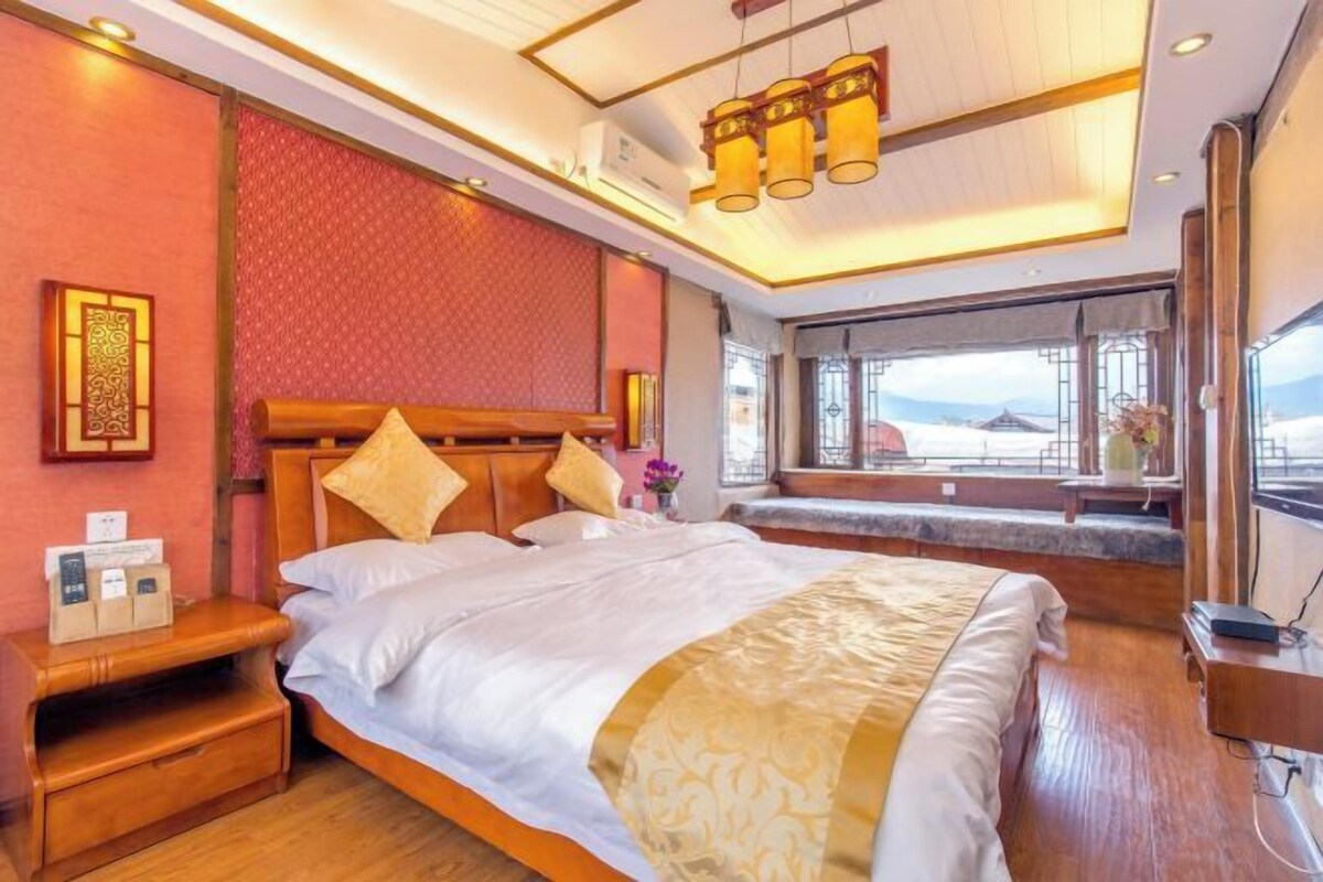 Habitación de hotel con una cama grande, mesitas de noche, una ventana con vistas y una lámpara en el techo.