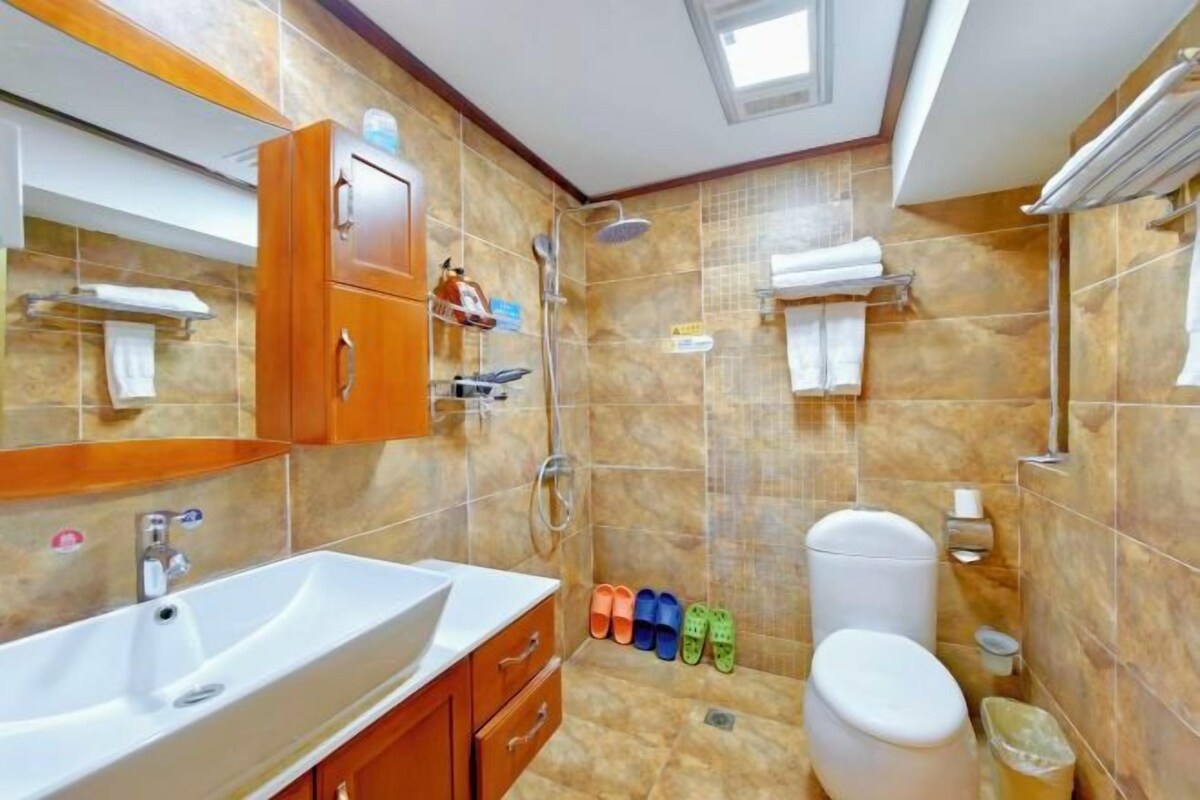 A bathroom with a sink, mirror, shower, toilet, and towel rack.