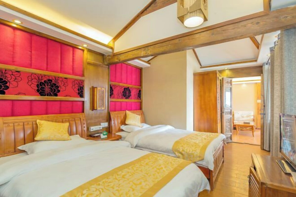 Quarto de hotel com duas camas, teto de madeira e parede vermelha.