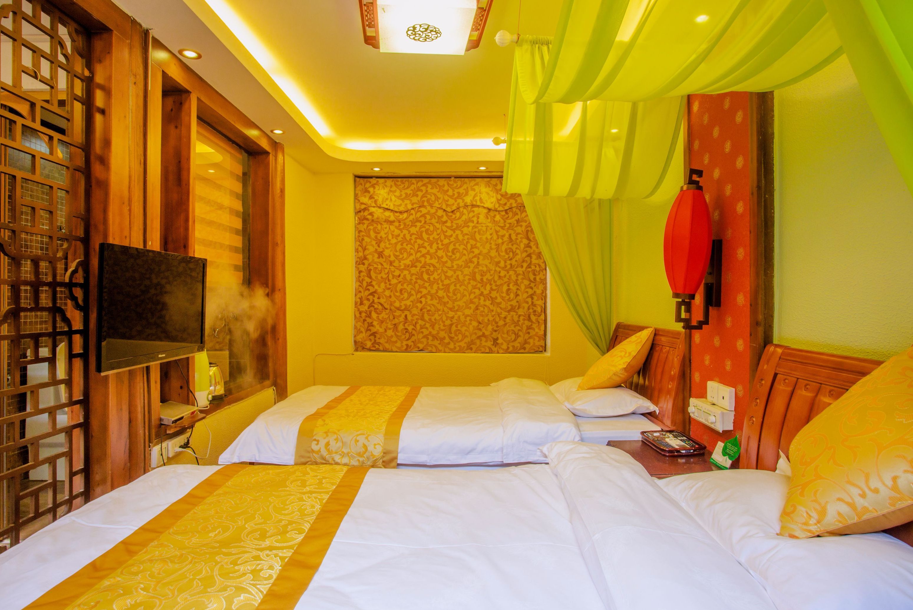 Habitación de hotel con dos camas, televisor, separador de madera y pared con diseño.