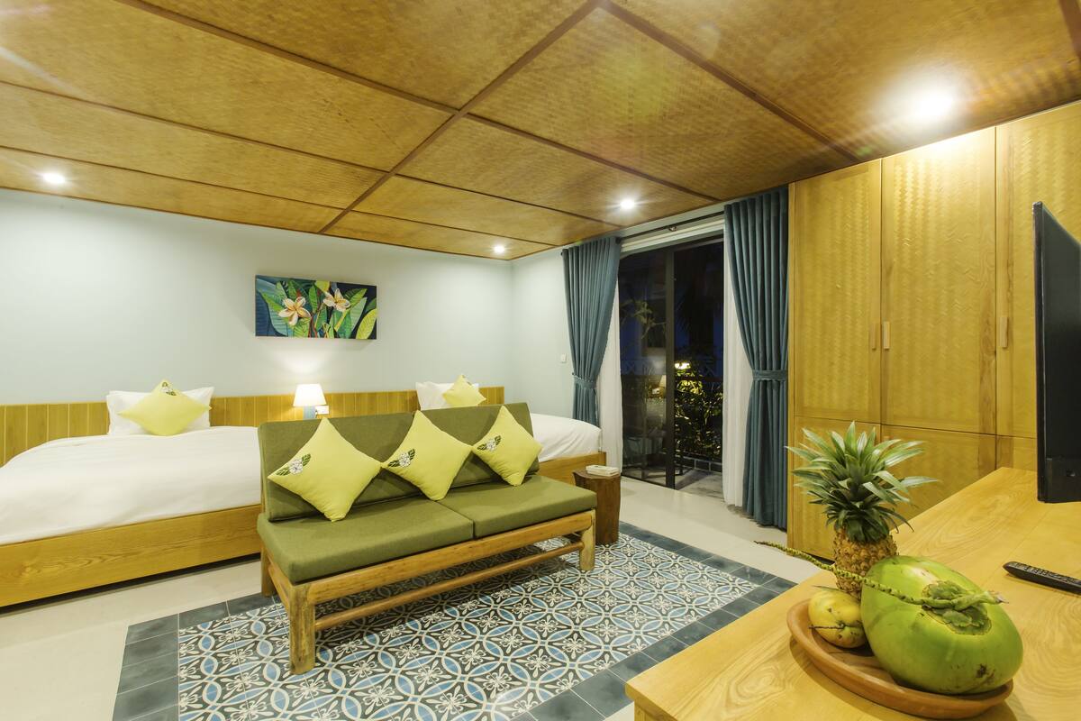 Una habitación de hotel con una cama, un sofá, una mesita con frutas y un televisor.