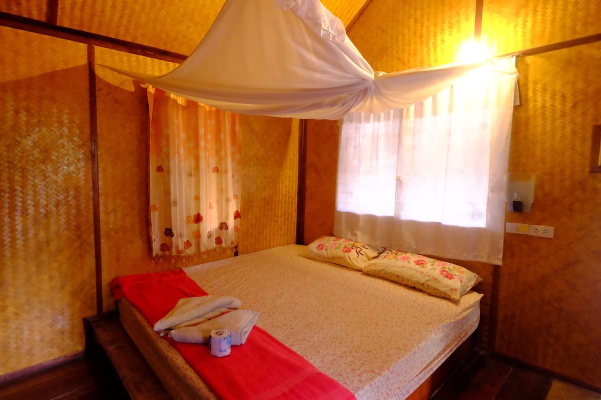 A room with a bed, a red blanket, a white canopy, and floral curtains.