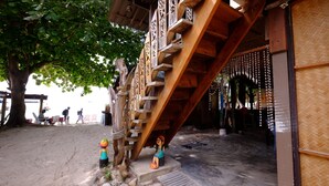 A wooden staircase with intricate carvings leading to a covered area with hanging decorations. - Seaside Resort Koh Lipe (Koh Lipe)