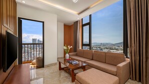 A modern living room with a large window, a sofa, a coffee table, and a TV.