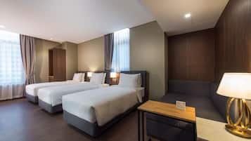 Habitación de hotel con dos camas, un sofá, una mesita y una lámpara.