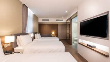 Habitación de hotel con dos camas, un televisor, una mesita de noche con lámpara y un ventanal grande con cortinas.