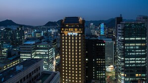Une vue urbaine mettant en évidence un grand bâtiment d’hôtel, portant l’inscription « SUITE HOTEL », qui présente un design moderne avec de nombreuses fenêtres et un toit plat.