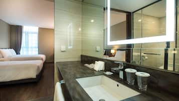 A hotel room with a large bed, a bathroom with a sink, mirror, and toiletries.