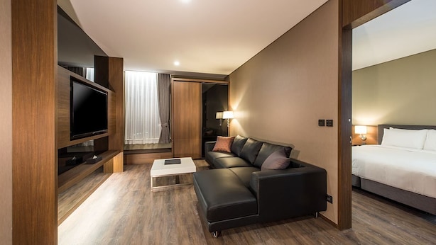 Une chambre d’hôtel moderne équipée d’un téléviseur à écran plat, d’un canapé, d’un lit et d’un plancher en bois.