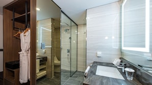Une salle de bain moderne avec une douche à parois de verre, un meuble-lavabo en bois et un peignoir suspendu à un porte-peignoir.