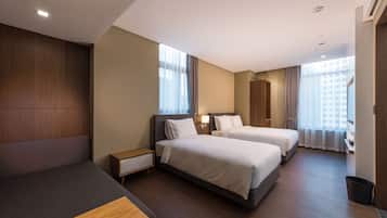 A modern hotel room with two beds, a sofa, a desk, and a large window with curtains.