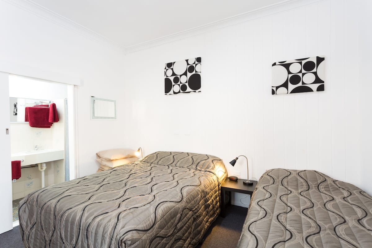 A hotel room with two beds, a bathroom, and artwork on the walls.