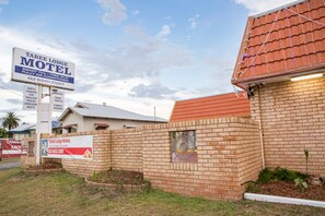 A brick motel with a signboard advertising amenities like parking, trailers, caravans, and boats.