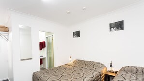 Un dormitorio con cama, mesita de noche y espejo.