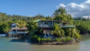 A floating house with multiple levels, connected by bridges, surrounded by lush greenery and water. - Edgewater Dive & Spa Resort (Puerto Galera)