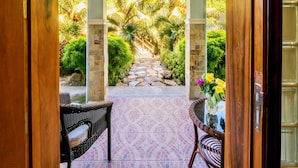 A covered outdoor area with a stone pathway leading to a seating area with wicker furniture and a glass table. - Edgewater Dive & Spa Resort (Puerto Galera)