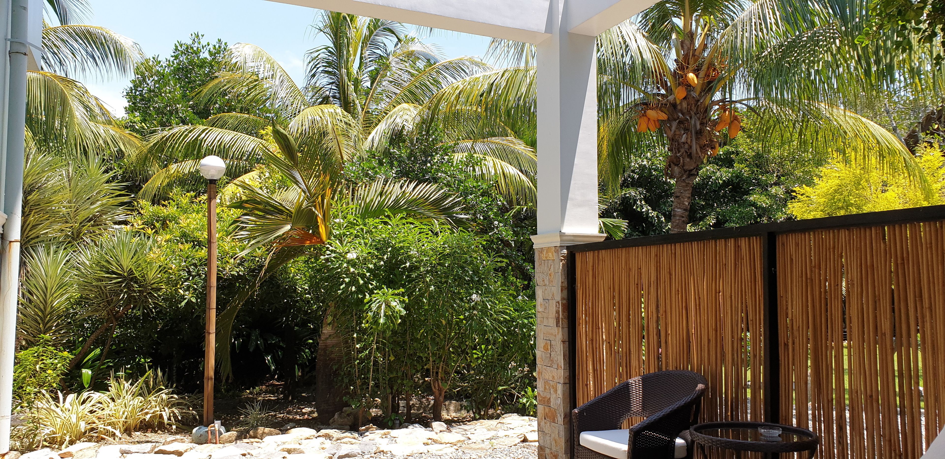 A covered outdoor area with a bamboo fence, a chair, and a table.