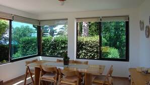 Une pièce dotée de grandes fenêtres, d’une table en bois et de chaises.