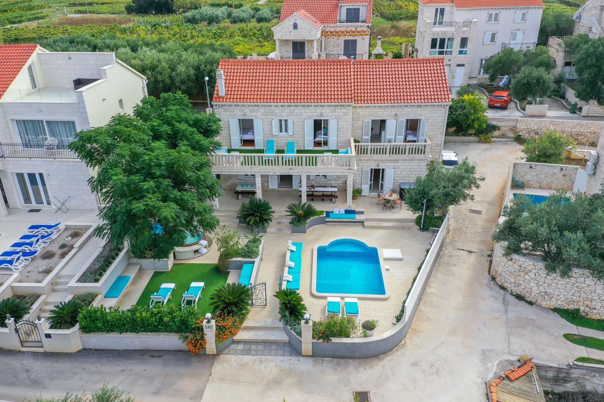 A large building with a swimming pool, outdoor seating, and a well-maintained garden.