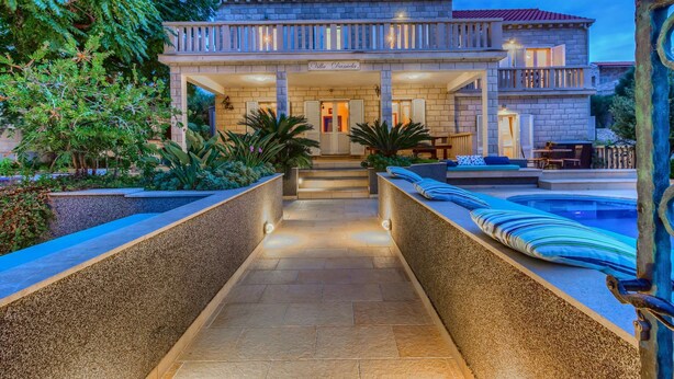 Eine Villa mit Pool, Sitzgelegenheiten im Freien und einem gut beleuchteten Eingang.
