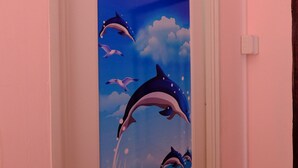 A door with a mural of dolphins jumping out of the water. - Sang Chan Hostel (Koh Lipe)