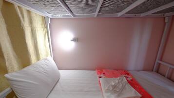 A single-bed room with a white mattress, a floral-patterned blanket, and a white pillow.