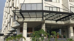 A modern multi-story building with a flat facade, large windows, and a covered entrance area with potted plants. - Rivoli Hotel Jakarta (Jakarta)