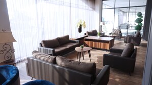 A modern living room with a sectional sofa, a coffee table, and a dining area with a wooden table and chairs. - Rivoli Hotel Jakarta (Jakarta)