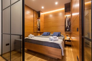 A modern bedroom with a wooden bed, a nightstand, and a wardrobe.