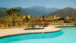 A swimming pool with two hot tubs, surrounded by a fence, with mountains in the background. - Sunny Palm Springs Solar Oasis 180° Mountains, 30ft Palms & Boulder Desertscape (Palm Springs)