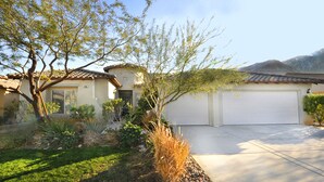 A residential house with a garage, a well-maintained lawn, and a tree in the front yard. - Sunny Palm Springs Solar Oasis 180° Mountains, 30ft Palms & Boulder Desertscape (Palm Springs)