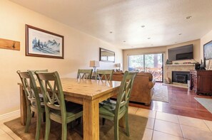 Un comedor con una mesa y sillas de madera, un sofá, una chimenea y un televisor.
