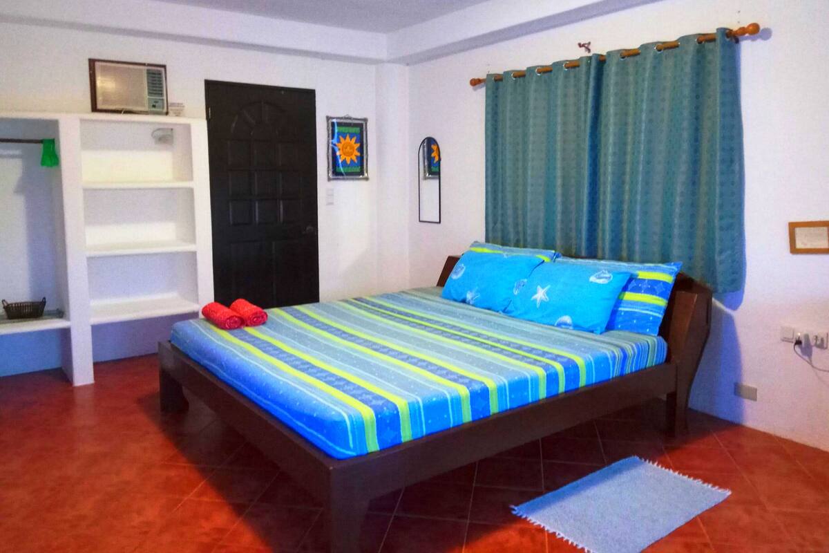 Ein Schlafzimmer mit Bett, Ablagefläche, Tür und Vorhängen.