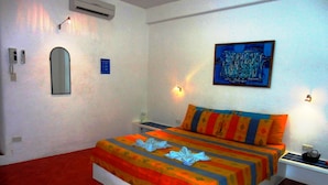 A hotel room with a bed, a nightstand, a wall-mounted air conditioner, a mirror, a painting, and a red tiled floor. - Aquarius Terraces Boutique Resort (Boracay Island)