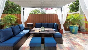 Une terrasse extérieure avec un ensemble de canapés, une table agrémentée d’une plante et un sol à motifs.