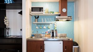 Une cuisine compacte équipée d’un four à micro-ondes, d’une machine à café et d’un petit réfrigérateur.