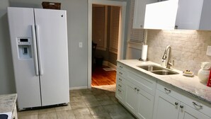 A kitchen with white cabinets, a stainless steel sink, and a built-in refrigerator.