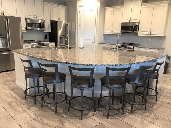 A modern kitchen with granite countertops, stainless steel appliances, and a central island with bar stools. - Access to 3 Private GOLF COURSES+Waterpark+POOL & SPA+Gameroom+THEATER+Disney (Four Corners)