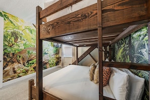 A bunk bed with a jungle-themed mural on the walls.