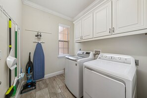 A laundry room with a washing machine, dryer, ironing board, and various cleaning tools. - Access to 3 Private GOLF COURSES+Waterpark+POOL & SPA+Gameroom+THEATER+Disney (Four Corners)