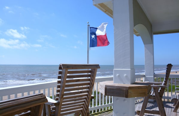 A wooden deck with a view of the ocean and a Texas flag.