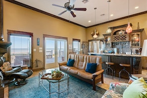A spacious living room with a leather sofa, a coffee table, and a dining area with bar stools.