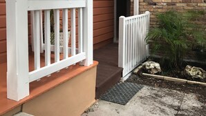 Uma casa com varanda, parede de tijolos e corrimão branco.
