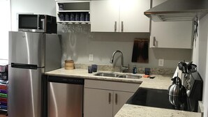 Uma cozinha moderna com eletrodomésticos de aço inoxidável, bancada de granito e chaleira de aço inoxidável.