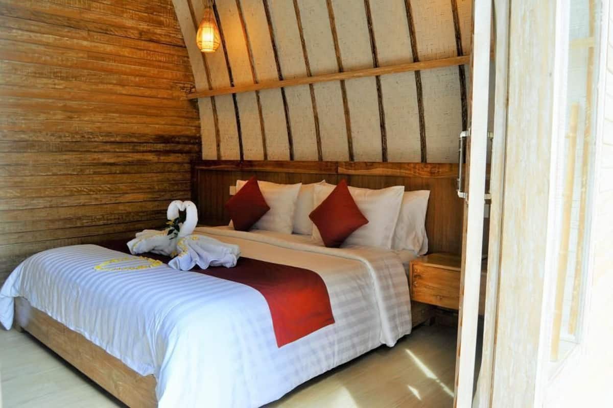 A wooden-paneled room with a bed, pillows, and a towel.