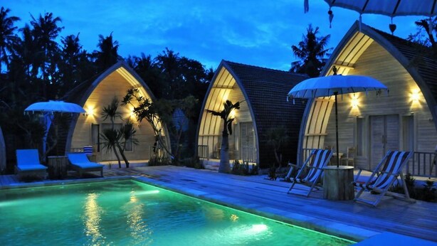 Zona de piscina con sillones de descanso y una piscina con luz verde.