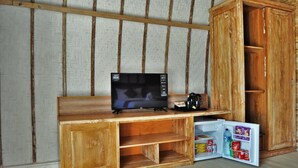 Una habitación pequeña con un escritorio de madera, televisor y un refrigerador.